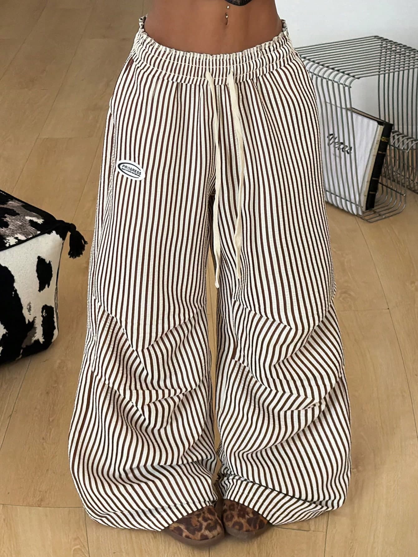 Full-length view of the same striped wide-leg cargo pants, showing the elasticated drawstring waist, the side pocket and the cuffed hems over leopard-print shoes.