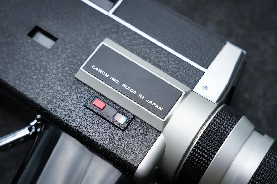 Close-up of the Canon Auto Zoom 518 SV's body, showing the silver "CANON INC. MADE IN JAPAN" badge beside the lens mount and power switch.